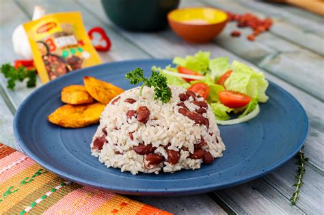 Fotografía de un plato servido de arroz con frijoles humeante con decoración de culantro fresco.