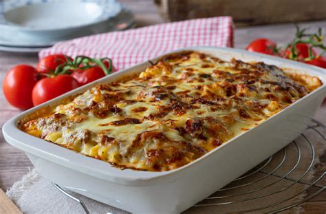 Lasaña lista para hornear con capas de jamón y queso