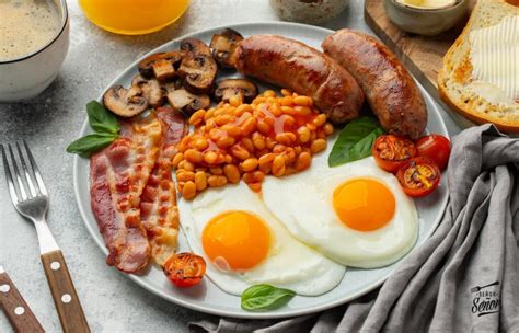 Ilustración de un desayuno inglés completo con huevos fritos, bacon, salchichas, tostadas y tomate.