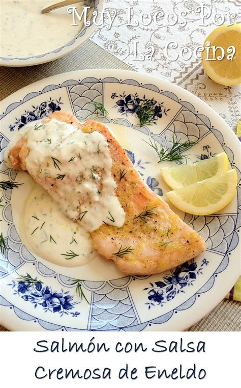 Plato terminado de salmón en trozos con salsa cremosa de limón y eneldo, decorado con rodajas finas de limón.