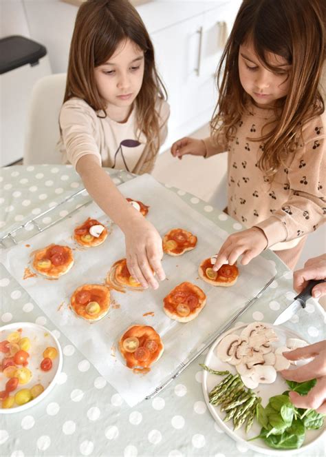 Niños decorando mini pizzas caseras con ingredientes coloridos