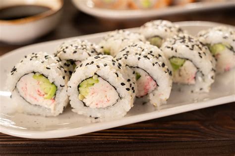 Primer plano de un rollo de sushi California con aguacate, surimi y queso crema visible