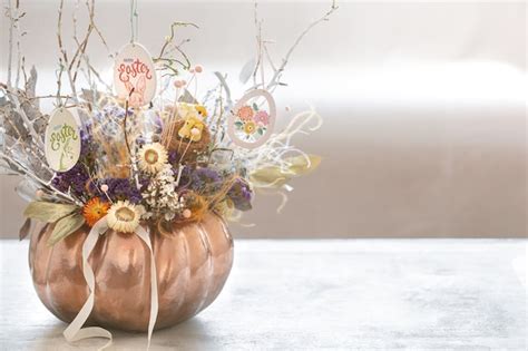 Arreglo otoñal con un frasco de vidrio con flores y una calabaza decorativa