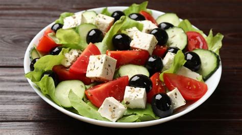 Primer plano de una ensalada mediterránea con queso feta y aceitunas negras, resaltando los colores vibrantes del tomate y pepino