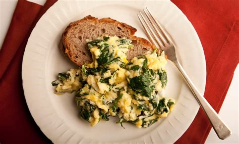 Plato de huevos revueltos con espinacas frescas y pan tostado