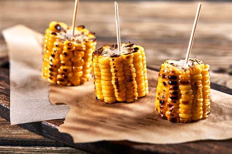Fotografía de mazorcas de maíz asadas a la parrilla con un toque de mantequilla y especias.