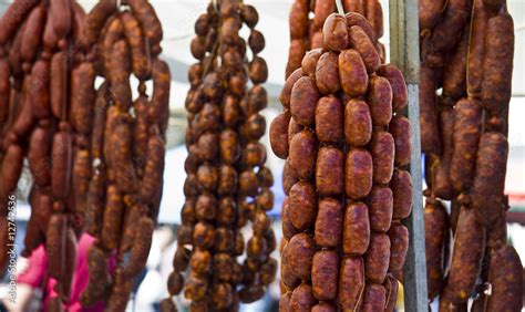 Chorizos curándose colgados, con etiquetas de peso