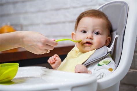 Bebé sonriente comiendo papilla en una trona