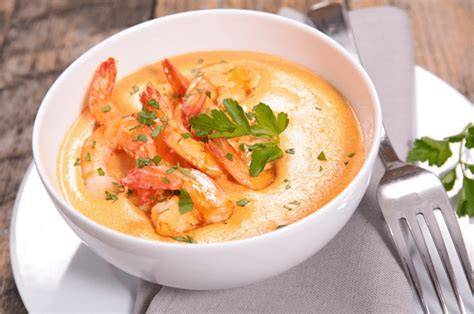 Bowl de crema de camarones con vegetales, decorada con perejil