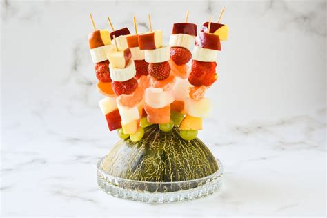 Varias brochetas de melón y jamón dispuestas en una fuente.