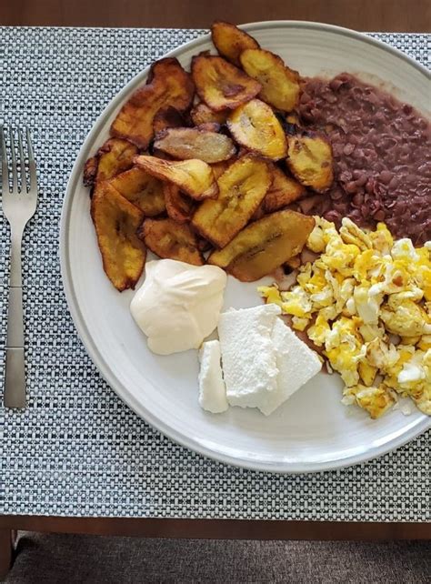 Plato de plátanos fritos con frijoles refritos, crema y aguacate