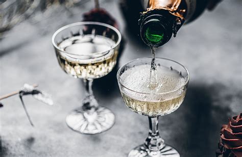 Fotografía profesional de postres servidos en copas con una botella de champagne de fondo
