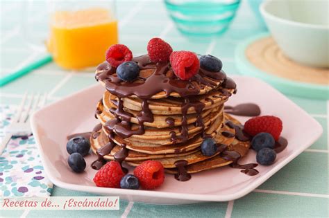 Plato con una torre de pancakes de plátano decorados con arándanos frescos y chocolate fundido