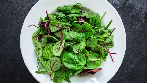 Plato con tallos de espinaca salteados y hojas