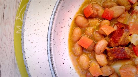 Plato de alubias con chorizo y tocino humeante, listo para servir