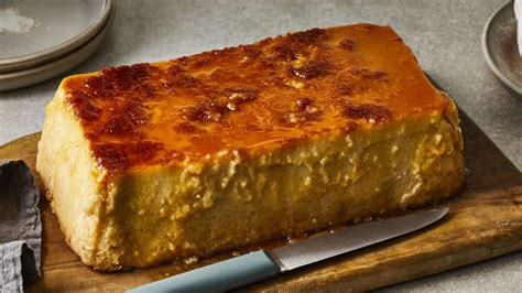 Budín de pan desmoldado, bañado en caramelo dorado, con nueces visibles en la superficie.