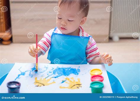 Niño pequeño pintando con las manos sobre un lienzo grande usando pintura de yogur de colores pastel