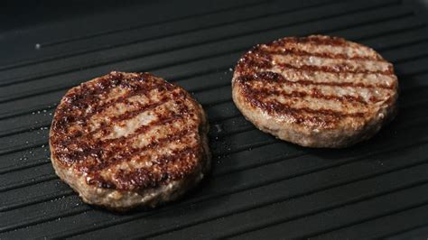 Proceso de cocción de hamburguesas árabes en una plancha.