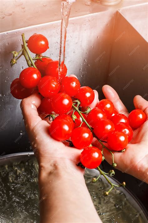 Manos lavando tomates frescos en un recipiente