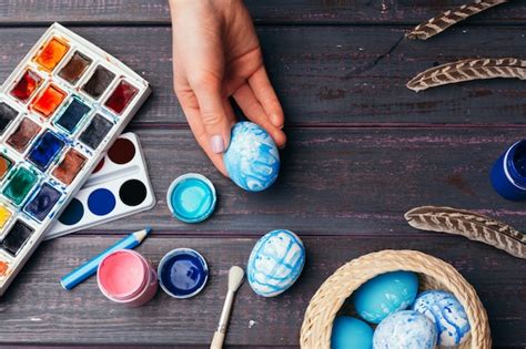 Detalle de manos pintando huevos de Pascua con pincel.