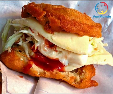 Foto de una arepa tumbarrancho abierta con sus múltiples rellenos y rebozado crujiente.
