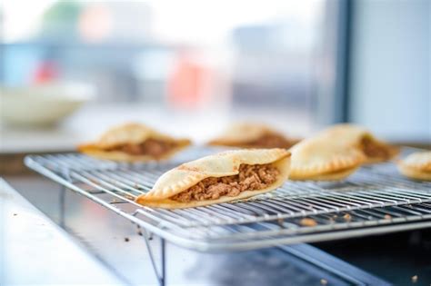Foto de empanadas recién horneadas reposando sobre una rejilla metálica para favorecer la ventilación.