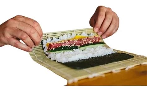Persona preparando un maki sushi con una esterilla de bambú (makisu)