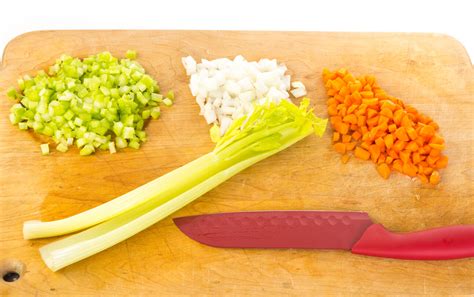 Fotografía de un mirepoix blanco ya cortado, mostrando cebolla, apio y puerro en dados uniformes listos para cocinar.