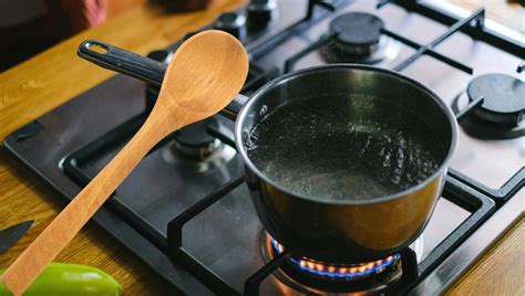 Primer plano de una cuchara removiendo suavemente huevos batidos en caldo hirviendo para crear hilos finos.