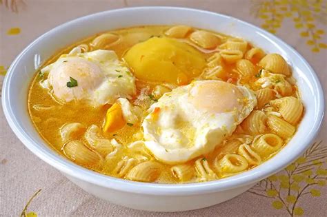 Plato de sopa de huevo con hortalizas verdes y un huevo revuelto, decorado con crutones.