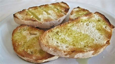 Foto de pan tostado con crema de aceite de oliva y una rama de romero