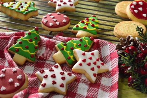 Foto de galletas navideñas de mantequilla decoradas con glaseado blanco sobre una mesa festiva.