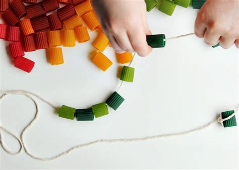 Niño divirtiéndose haciendo un collar de pasta