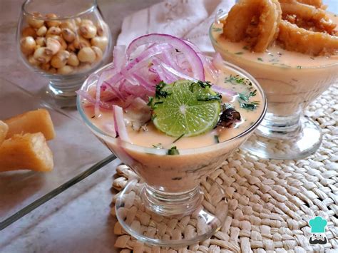 Mesa con varios platos pequeños de leche de tigre como aperitivo, decorados con cilantro y ají.