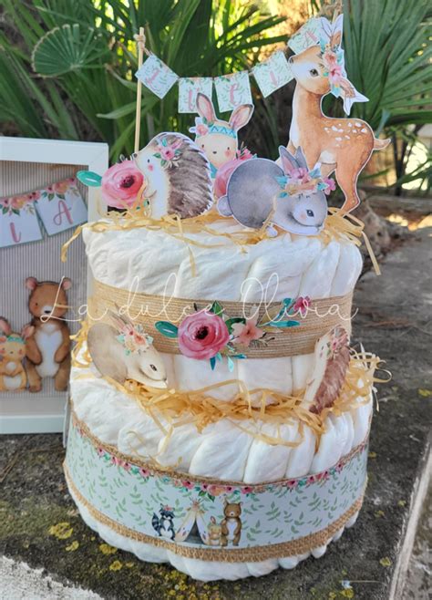 Foto de una tarta de pañales decorada con cintas y pequeños juguetes.