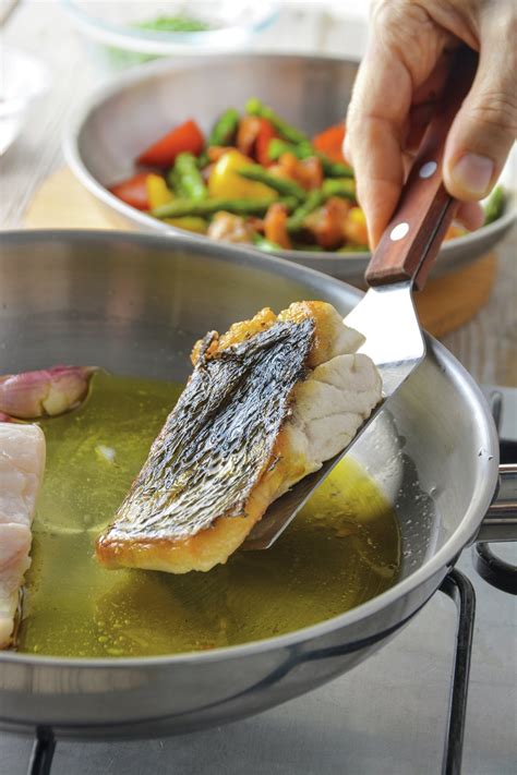 Pescado blanco sellándose ligeramente en una sartén con aceite