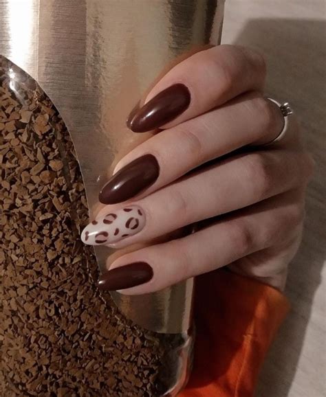Uñas color chocolate con pequeños detalles florales