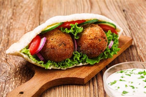 Fotografía de falafels dorados recién fritos servidos en pan de pita con verduras frescas