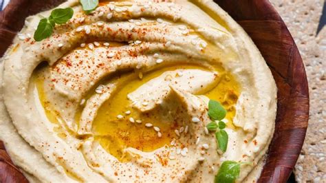 Foto de un bol de hummus tradicional adornado con perejil y un chorrito de aceite de oliva.