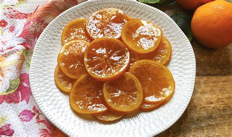 Primer plano de rodajas de naranja confitada, brillantes y caramelizadas.