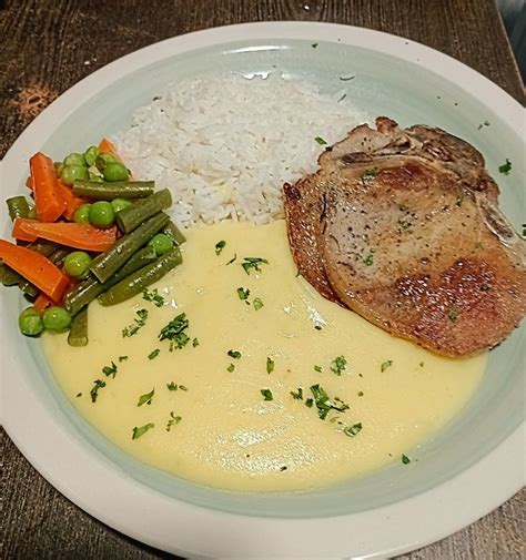 plato con chuleta de cerdo asada, puré de papas y una ramita de perejil