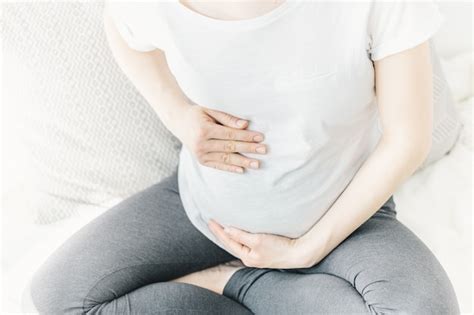 Mujer embarazada en el quinto mes, sonriendo y tocándose la barriga