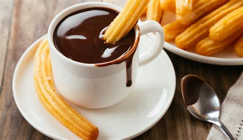 Un plato de churros recién hechos con una taza de chocolate caliente.