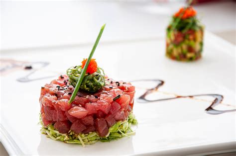 Tartar de atún y aguacate emplatado con aro, decorado con sésamo