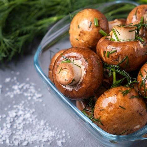 Primer plano de champiñones frescos listos para ser escalfados, con ingredientes aromáticos alrededor.