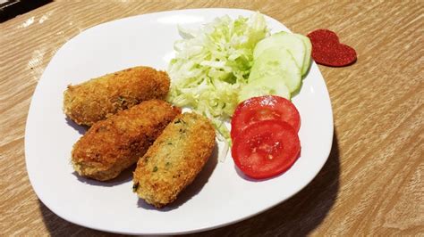 Plato servido con croquetas de atún doradas acompañadas de una ensalada fresca
