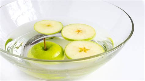Rodajas finas de manzana cocidas en un bol con agua y limón