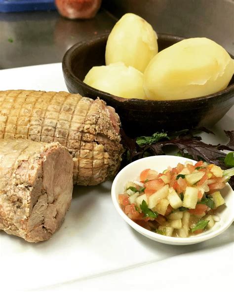 Plato de arrollado huaso con papas cocidas y pebre, con un enfoque rústico.