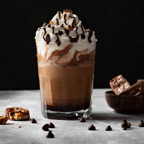 Fotografía profesional de un batido de chocolate en un vaso de cristal rodeado de almendras y cacao