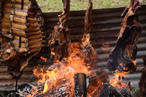 Fotografía de carne a la mamona asándose en estacas alrededor de una hoguera